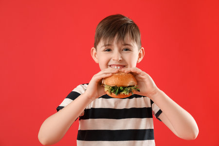 Little boy with tasty vegan burger on color backgroundの写真素材