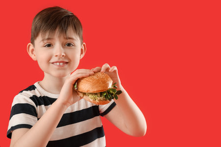 Little boy with tasty vegan burger on color backgroundの写真素材