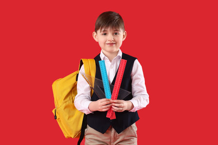 Little schoolboy with rulers on color backgroundの写真素材