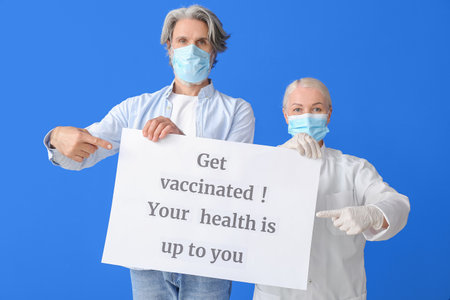 Doctor and patient holding poster with text GET VACCINATED. YOUR HEALTH IS UP TO YOU on color backgroundの写真素材