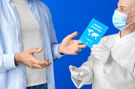 Doctor giving patient his immune passport on color backgroundの写真素材