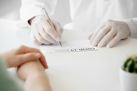 Doctor filling in form of International Certificate of Vaccination in clinic, closeup