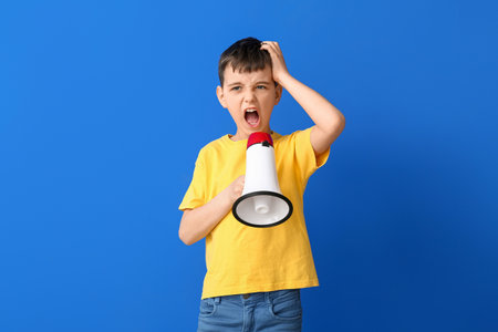 Protesting little boy with megaphone on color backgroundの写真素材