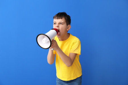 Protesting little boy with megaphone on color backgroundの写真素材