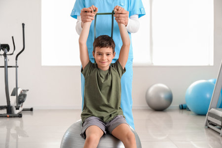 Physiotherapist working with boy in rehabilitation centerの写真素材