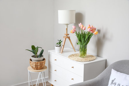 Bouquet of tulip flowers on chest of drawers near white wallの写真素材