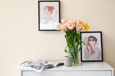 Bouquet of tulip flowers and magazine on chest of drawers near color wallの写真素材