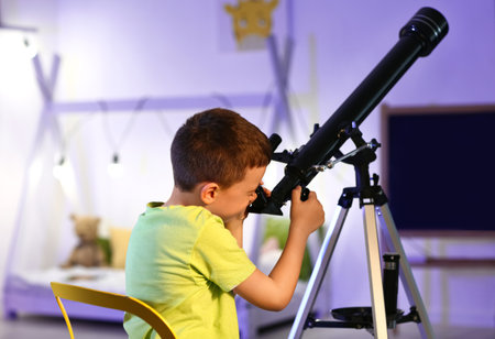 Little boy with telescope looking at the stars in the eveningの写真素材