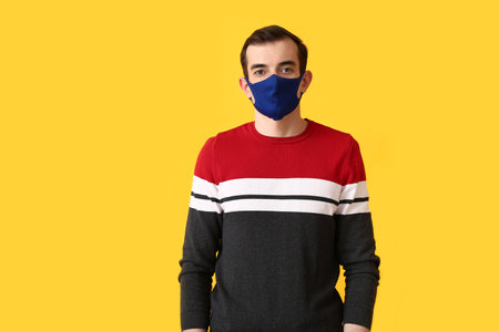 Young man wearing medical mask on color backgroundの写真素材