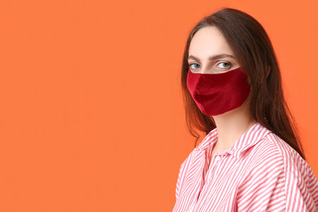Young woman wearing medical mask on color backgroundの写真素材