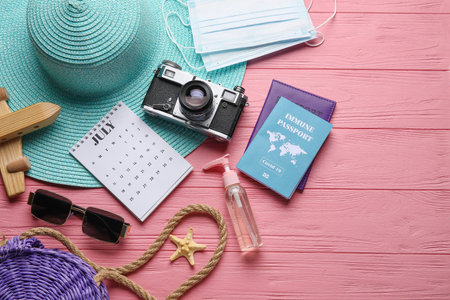 Calendar with beach accessories, medical masks and immune passport on color wooden backgroundの写真素材