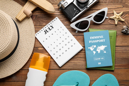 Calendar with beach accessories and immune passport on wooden backgroundの写真素材