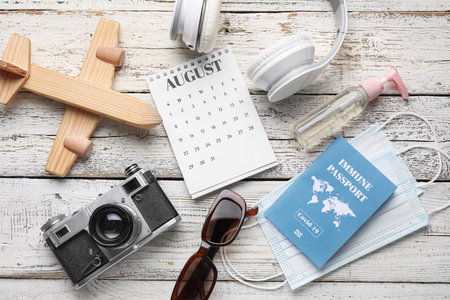 Calendar with travel accessories, medical masks and immune passport on white wooden backgroundの写真素材