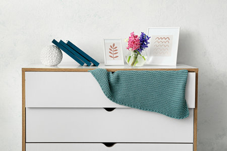 Chest of drawers with plaid and decor near light wallの写真素材