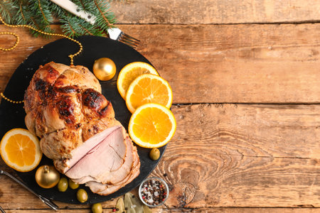 Plate with tasty ham, olives, orange and Christmas balls on wooden tableの写真素材