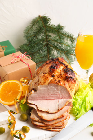 Plate with tasty Christmas ham, olives, orange and lettuce on white wooden tableの写真素材