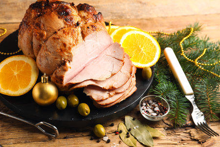 Plate with tasty ham, olives, orange and Christmas decor on wooden table, closeupの写真素材