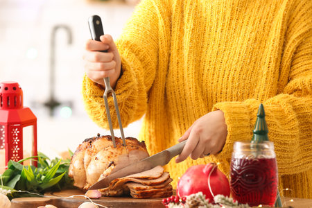 Woman cutting tasty ham at table on Christmas eve, closeupの写真素材