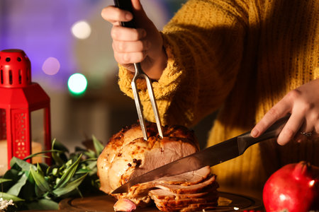 Woman cutting tasty ham at table on Christmas eve, closeupの写真素材