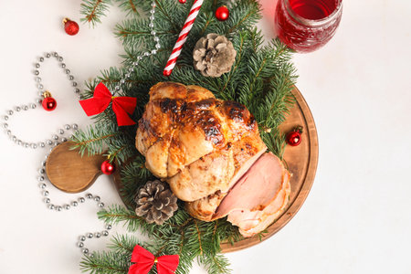 Board with tasty ham, fir branches, cones and Christmas balls on white tableの写真素材