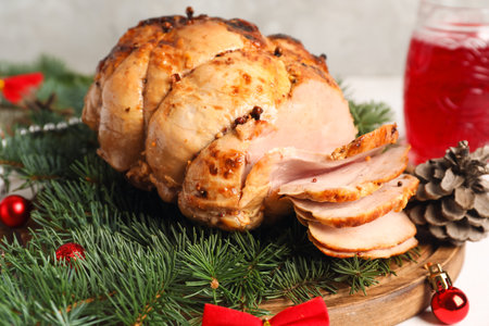 Board with tasty ham, fir branches and Christmas balls on white table, closeupの写真素材