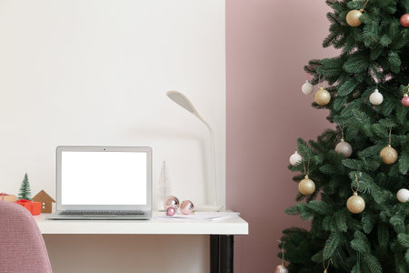 Laptop with Christmas gifts on table in officeの写真素材