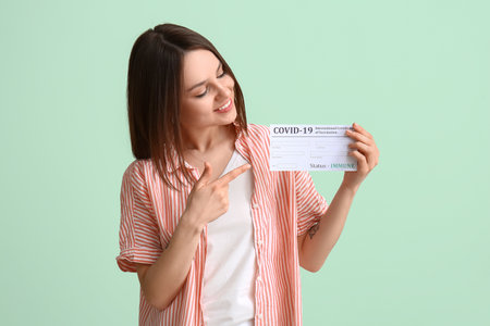 Young woman with International Certificate of Vaccination on color backgroundの写真素材