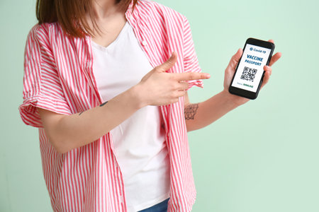 Young woman with electronic immune passport on color backgroundの写真素材