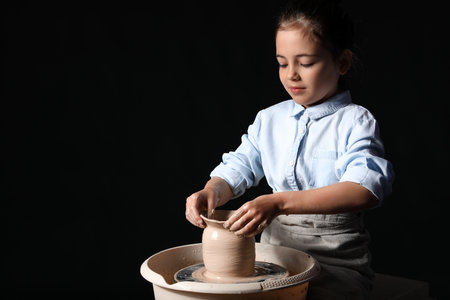 Little girl making ceramic pot on dark backgroundの写真素材