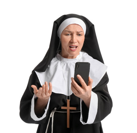 Displeased mature nun using mobile phone on white backgroundの写真素材