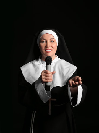 Mature nun with microphone singing on dark backgroundの写真素材