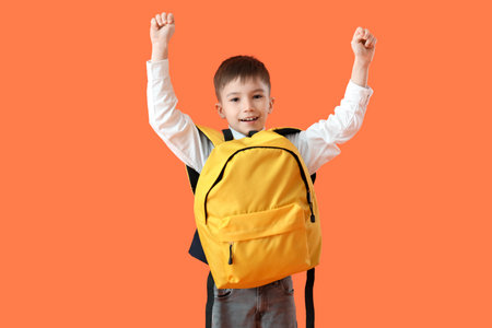 Little schoolboy with backpack on color backgroundの写真素材