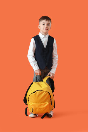 Little schoolboy with backpack on color backgroundの写真素材