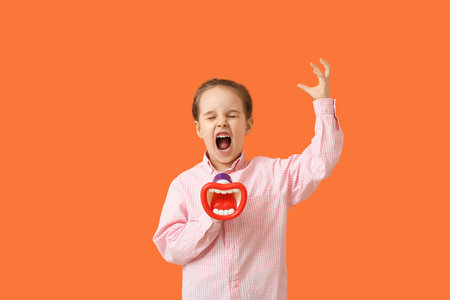 Angry little girl shouting into megaphone on color backgroundの写真素材