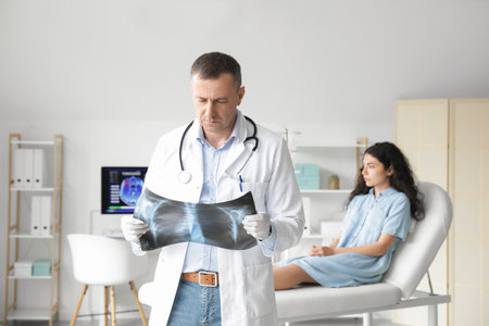 Mature doctor studying x-ray image of lungs in clinicの写真素材