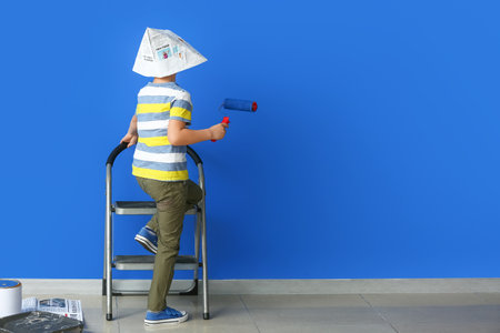 Little painter with roller near color wallの写真素材