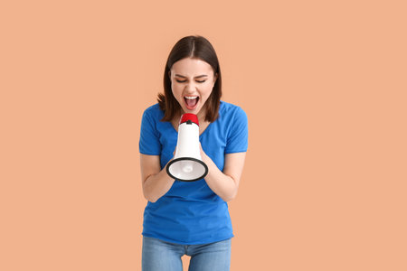 Protesting young woman with megaphone on color backgroundの写真素材