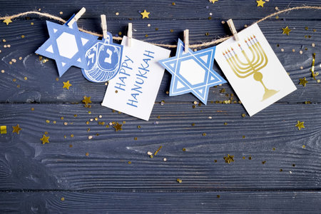 Card with text HAPPY HANUKKAH, pictures, clothespins and rope on dark wooden backgroundの写真素材