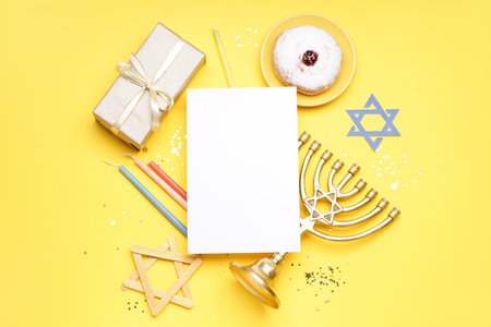 Blank card with menorah, donut, candles and gift for Hannukah celebration on yellow backgroundの写真素材