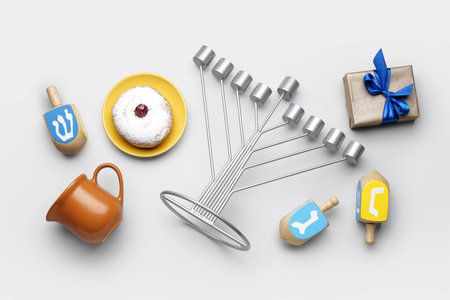 Menorah with donut, jug, gift and dreidels for Hannukah celebration on gray backgroundの写真素材