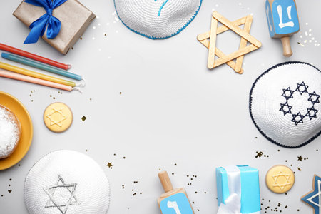 Frame made of kipa, cookies, dreidels and gifts for Hannukah celebration on gray backgroundの写真素材