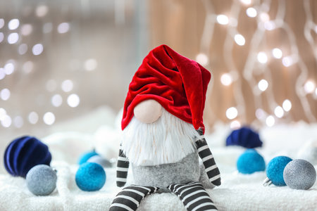 Christmas gnome and balls on light fabric against glowing lightsの写真素材