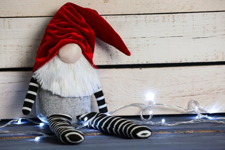 Funny Christmas gnome and glowing lights on wooden table