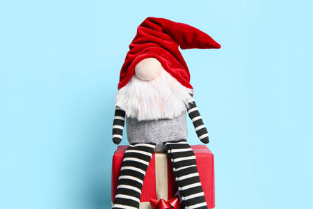 Christmas gnome on gift box against color backgroundの写真素材