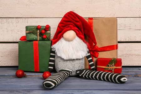 Christmas gnome and gift boxes on color wooden tableの写真素材