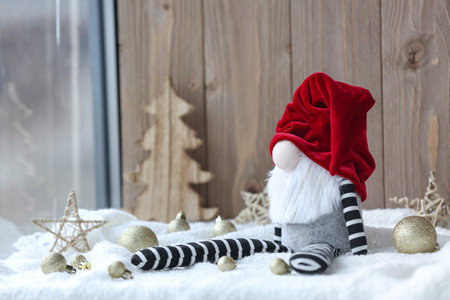 Christmas gnome and decorations on light fabric against wooden backgroundの写真素材