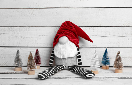 Christmas gnome toy and decorative trees on light wooden backgroundの写真素材