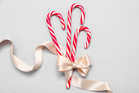 Sweet candy canes with ribbon on light backgroundの写真素材