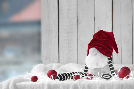 Christmas gnome toy and balls on white fabric against light wooden backgroundの写真素材