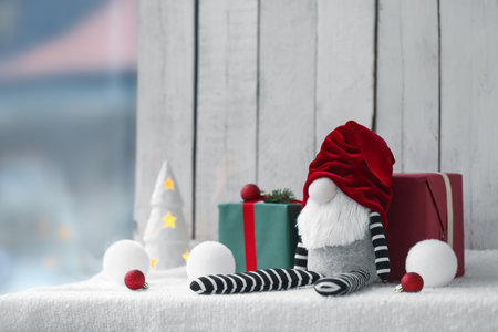 Christmas gnome toy, gift boxes and decorations on white fabric against light wooden backgroundの写真素材